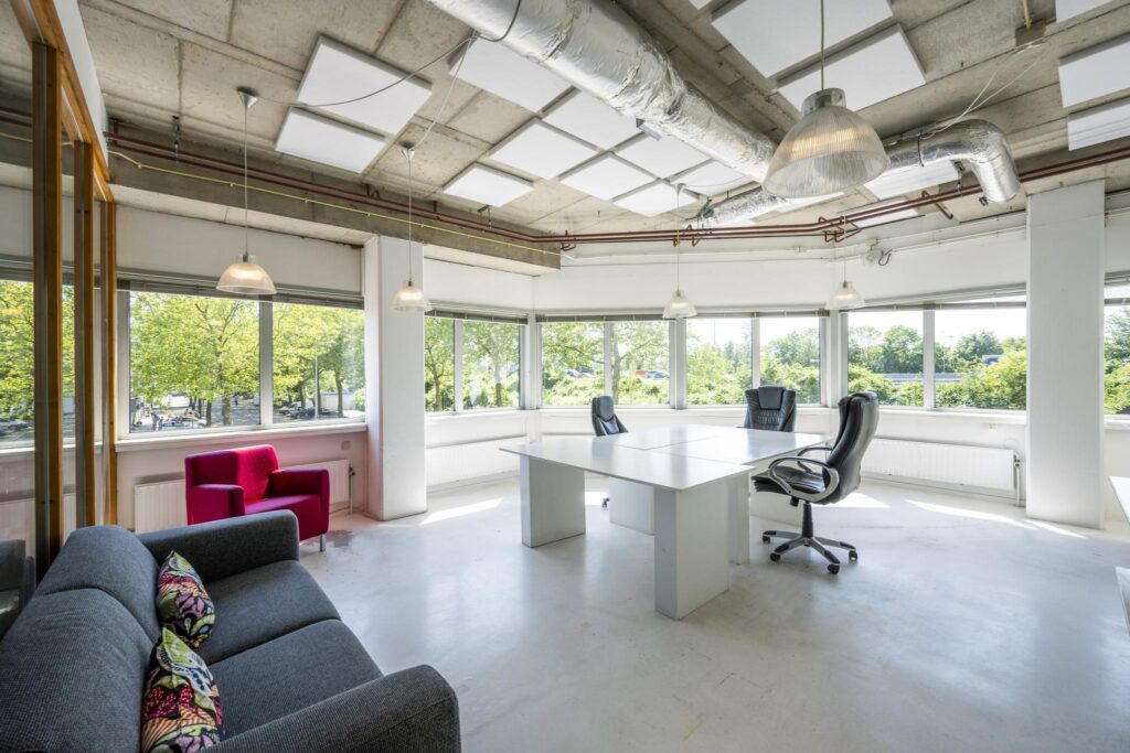Modern en licht kantoorpand aan de Anthony Fokkerweg met grote ramen, vergadertafel en loungehoek.